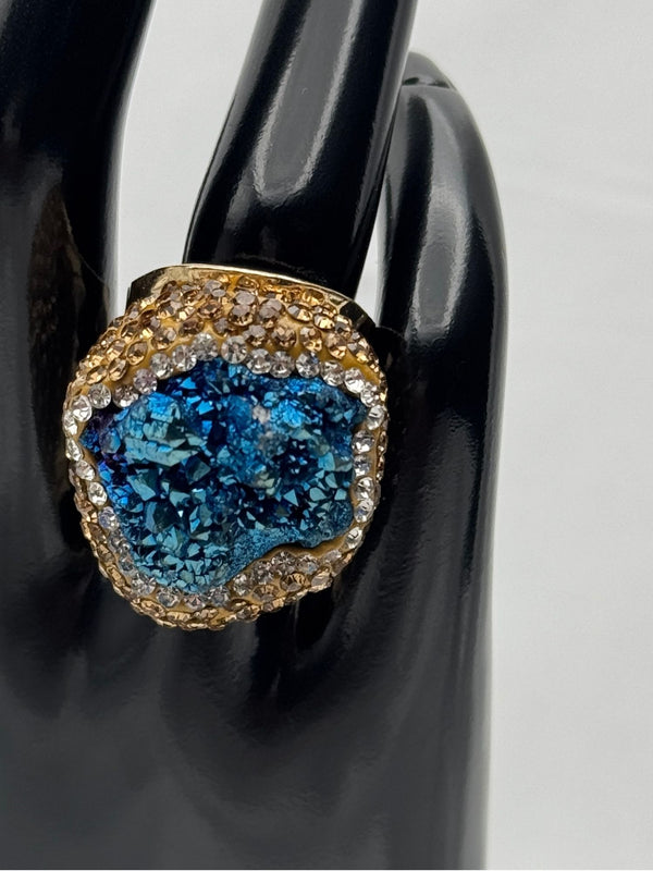 Earthy, reminiscent, bold design, oceanic blue hue center stone surrounded by textured, gold-toned settingone size fits allstatement ringvacation ring bold ringunique designgold jewelry gold ring earthy ring
