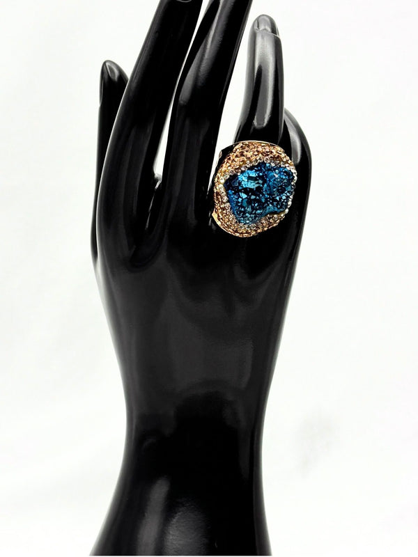 Earthy, reminiscent, bold design, oceanic blue hue center stone surrounded by textured, gold-toned settingone size fits allstatement ringvacation ring bold ringunique designgold jewelry gold ring earthy ring