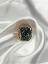 Earthy, reminiscent, bold design, oceanic blue hue center stone surrounded by textured, gold-toned settingone size fits allstatement ringvacation ring bold ringunique designgold jewelry gold ring earthy ring