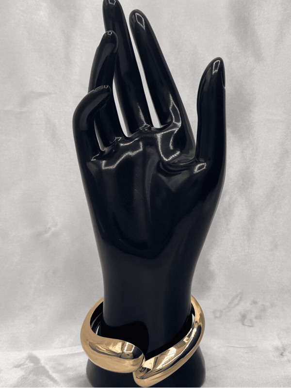 Golden embrace cuff braceletChunky gold cuff jewelryInterlocking gold-tone braceletSculptural gold bangleElegant statement braceletMinimalist gold arm accessoryModern gold cuff jewelryBold and chic wrist cuffPolished gold bracelet for womenTimeless gold statement jewelry