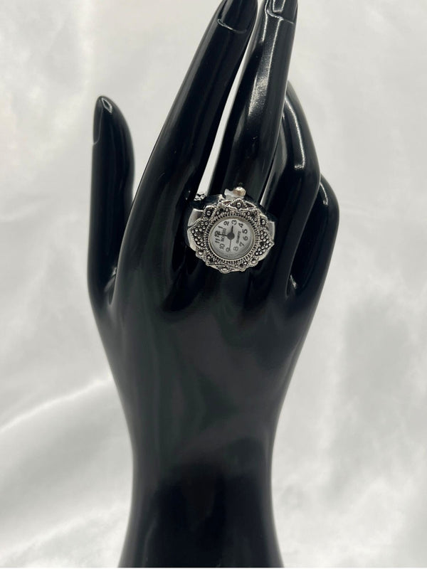 vintage-style silver-tone watch ring. Ornate bezel with intricate detailing. The round white dial with clear black numerals provides easy readability. Antique-inspired design. Perfect for vintage jewelry lovers who appreciate a statement piece with a practical twist.vintage-style watch ringsilver-tone watch ringornate bezel ring watchantique-inspired watch ringwomen’s fashion ring watchfunctional jewelry with vintage designquartz ring watch for womenstylish timepiece ringunique silver watch ring