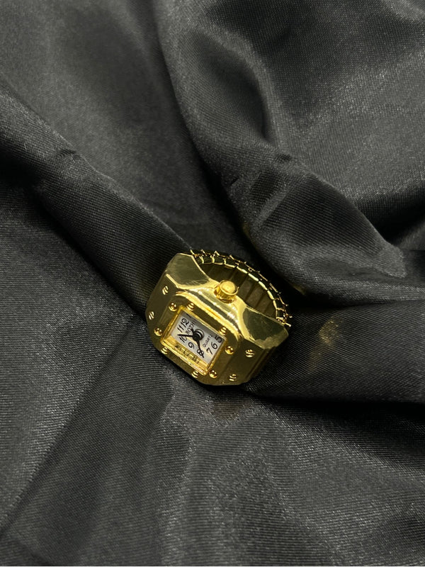 Gold-Tone Square Watch Ring with White Dial. One sizesquare face with black numerals on a white dial, this piece offers a modern twist on a classic designgold-tone watch ringsquare face ring watchstylish gold watch ring for womenelegant quartz watch ringfashion-forward timepiece jewelrygold statement ring with white dialwomen’s fashion accessory watchfunctional jewelry with gold designtrendy watch ring for womenluxury gold-tone ring watch