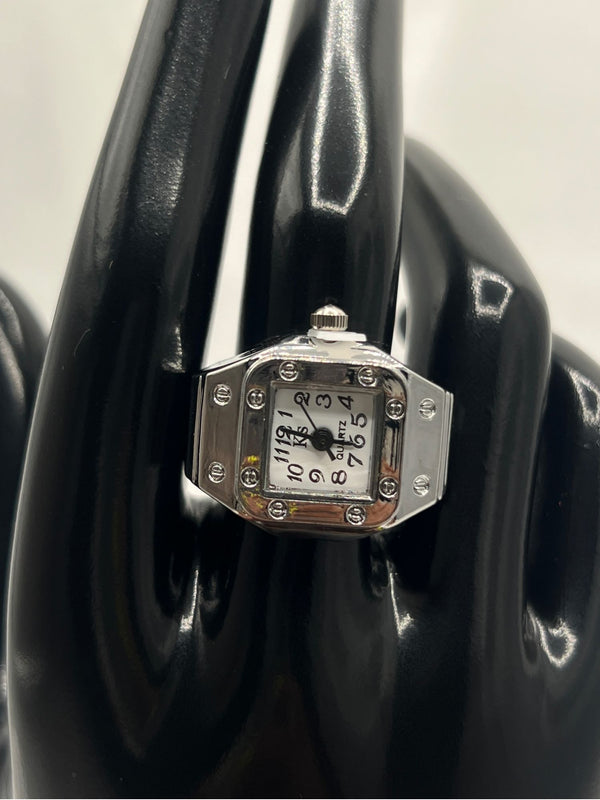 Silver-Tone Watch Ring with White Face. Unique, silver-tone, watch ring, featuring a chic square face with clear, easy-to-read black numerals. Combining the functionality of a watch with the elegance of a ring. Ffashion with a practical twist. silver-tone watch ringsquare face watch ringstylish watch ring for womenrhinestone watch ringelegant watch ring with white dialfunctional jewelryquartz watch ringstatement timepiece jewelrywomen’s fashion ring watchunique silver-tone ring. One-size.