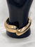 Golden embrace cuff braceletChunky gold cuff jewelryInterlocking gold-tone braceletSculptural gold bangleElegant statement braceletMinimalist gold arm accessoryModern gold cuff jewelryBold and chic wrist cuffPolished gold bracelet for womenTimeless gold statement jewelry
