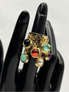  luxurious gold-tone band adorned with multiple vibrant, natural-colored stone charms. Each charm showcases a different gem, including shades of green, red, purple, black, and white with aunique dangling design. statement ringgold-tone ring with charmsmulticolor stone ringadjustable gemstone ringboho chic jewelrybold fashion ringeclectic ring designnatural stone jewelryunique tassel ringtrendy women's accessories